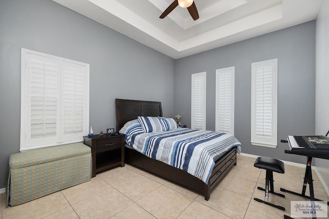 tiled bedroom with ceiling fan and a tray ceiling