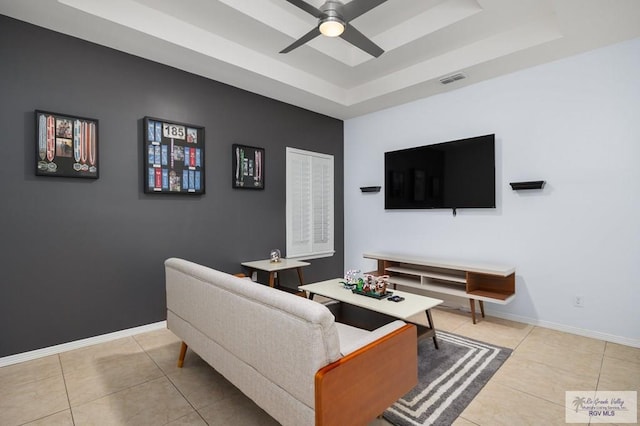 tiled living room featuring ceiling fan and a tray ceiling