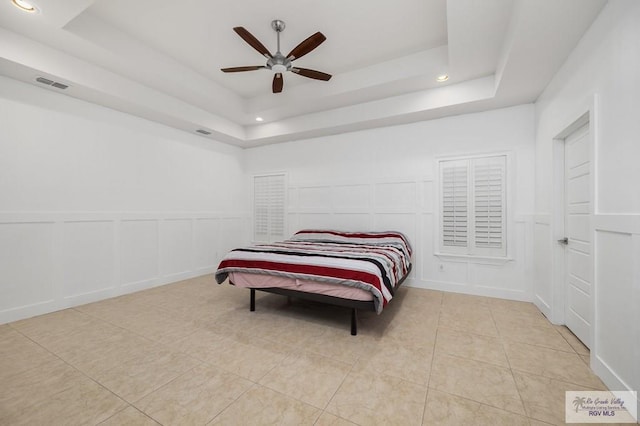 tiled bedroom featuring a raised ceiling and ceiling fan