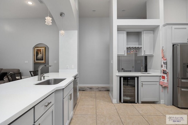 kitchen with decorative light fixtures, stainless steel appliances, light tile patterned floors, wine cooler, and sink