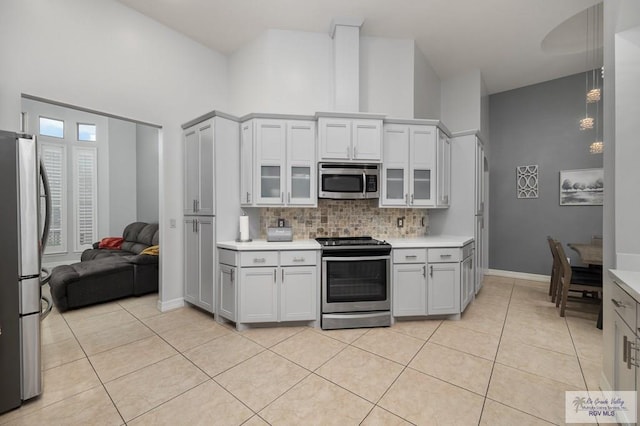 kitchen featuring stainless steel appliances, white cabinetry, light tile patterned flooring, and backsplash