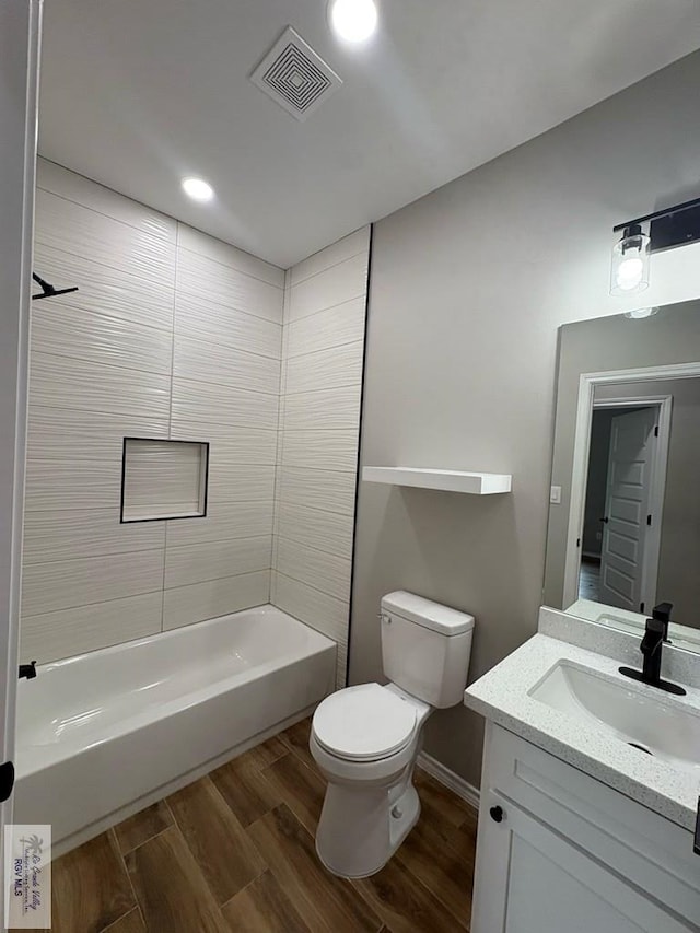 full bath featuring toilet, wood finished floors, vanity, visible vents, and shower / bathing tub combination