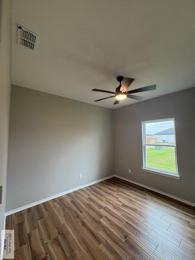 spare room featuring a ceiling fan, visible vents, dark wood finished floors, and baseboards