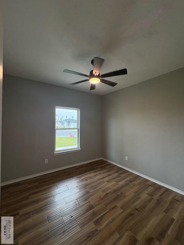 spare room with dark wood finished floors, a ceiling fan, and baseboards