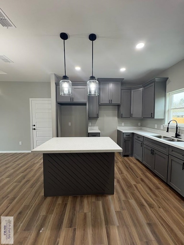 kitchen with dark wood-style flooring, gray cabinets, a sink, and decorative light fixtures