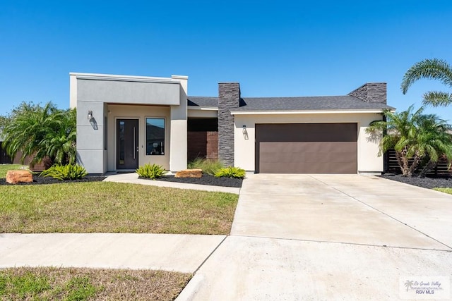 contemporary house featuring a garage, a front lawn, concrete driveway, and stucco siding