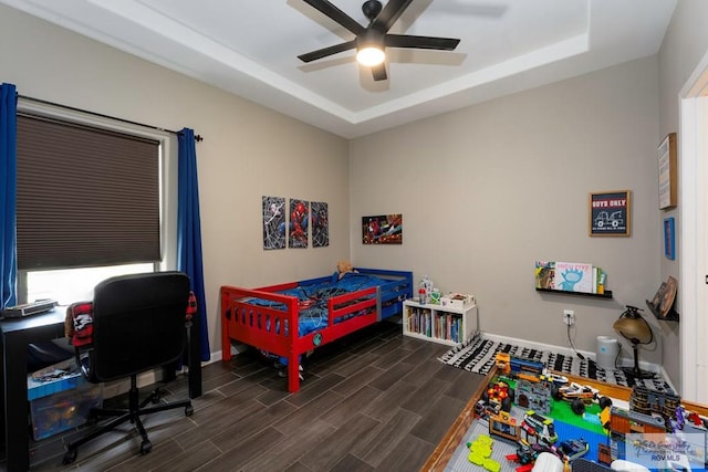 bedroom featuring ceiling fan, wood finish floors, a raised ceiling, and baseboards