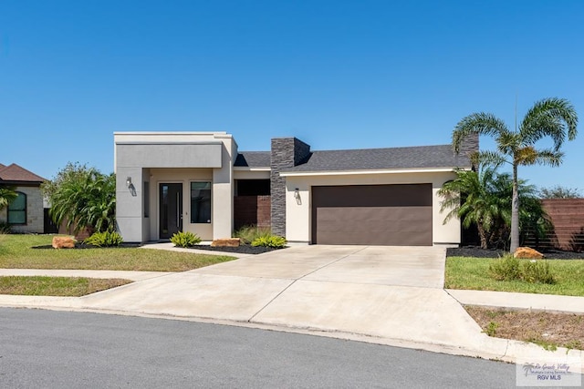 view of front facade with a garage, concrete driveway, and stucco siding