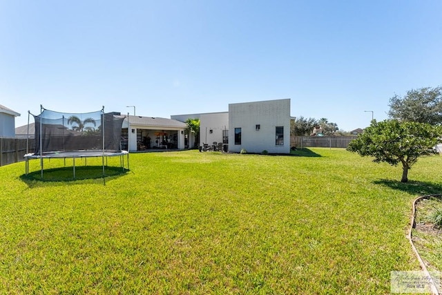 view of yard with a trampoline and fence