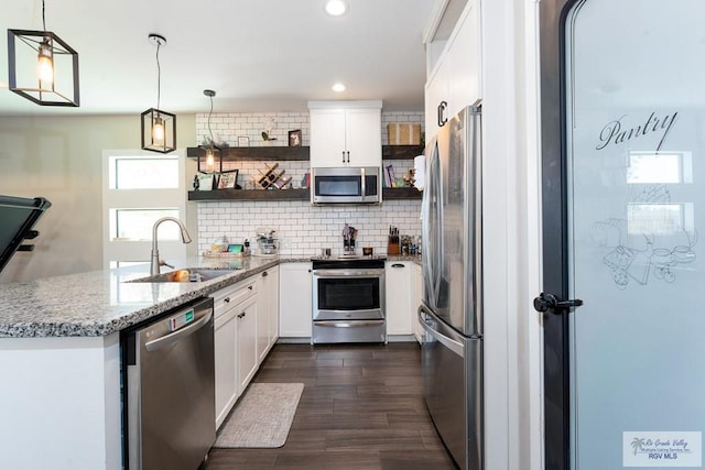 kitchen featuring light stone counters, a sink, appliances with stainless steel finishes, open shelves, and tasteful backsplash