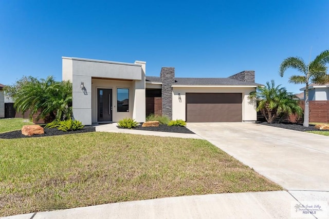 contemporary house featuring a garage, fence, concrete driveway, stucco siding, and a front lawn