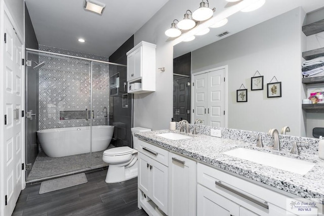 bathroom with double vanity, wood finished floors, a stall shower, and a sink