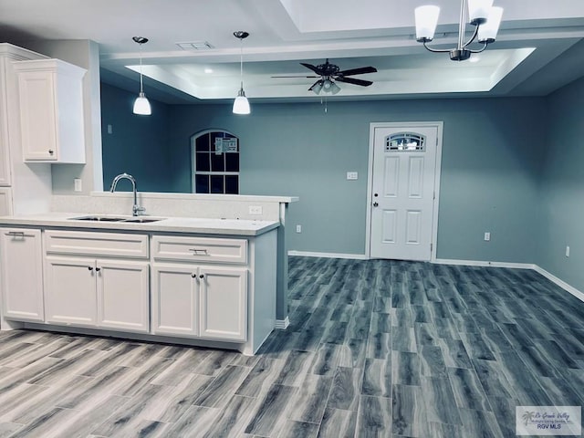 kitchen featuring white cabinets, hanging light fixtures, a raised ceiling, and sink