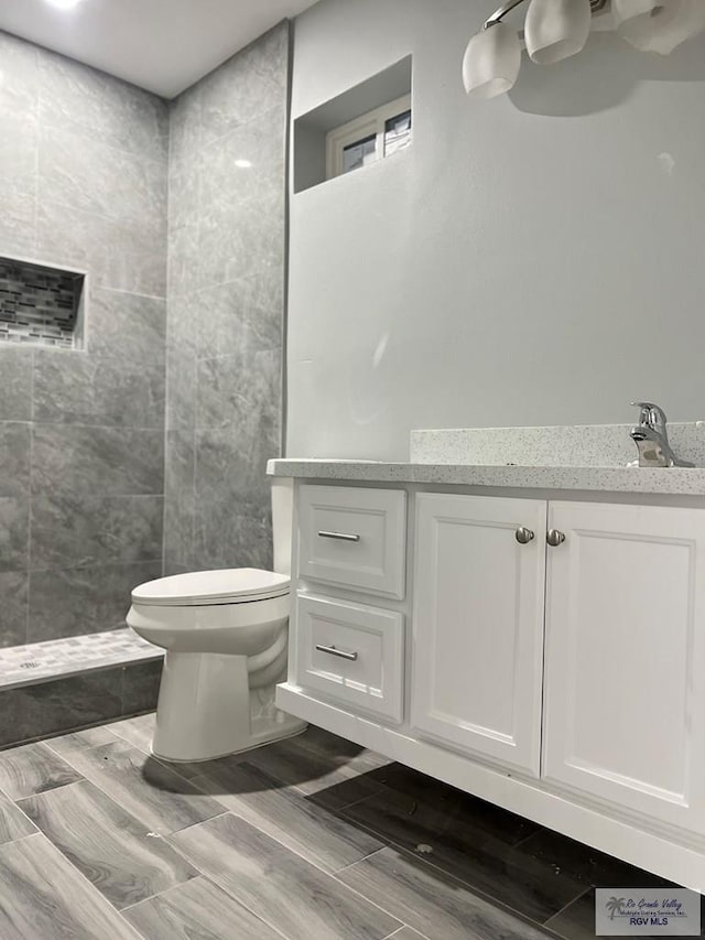 bathroom featuring toilet, walk in shower, and vanity