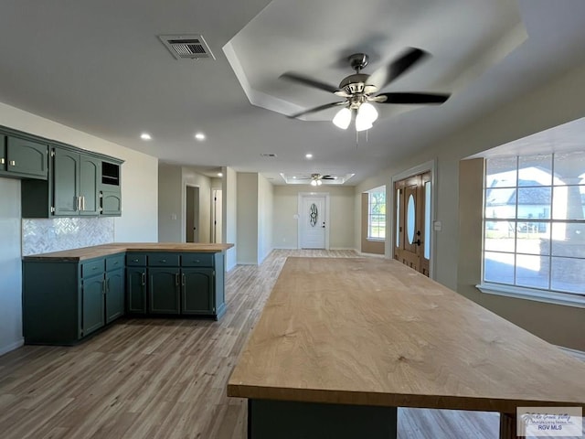 kitchen featuring ceiling fan, wood counters, green cabinets, light hardwood / wood-style flooring, and decorative backsplash