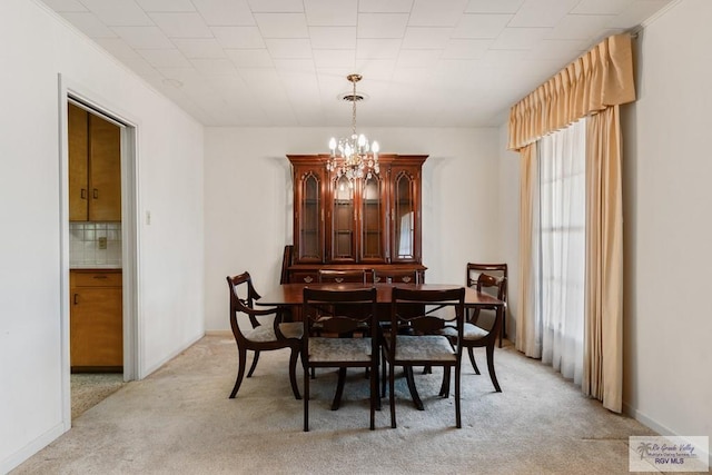 carpeted dining room with crown molding and an inviting chandelier