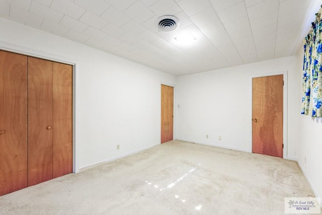 unfurnished bedroom with light colored carpet and a closet