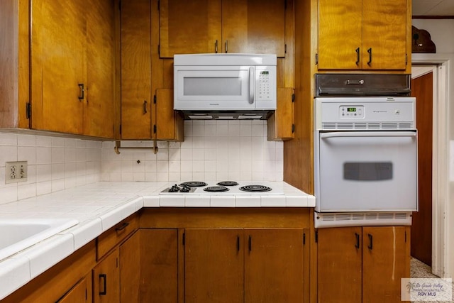 kitchen with backsplash, tile countertops, sink, and white appliances