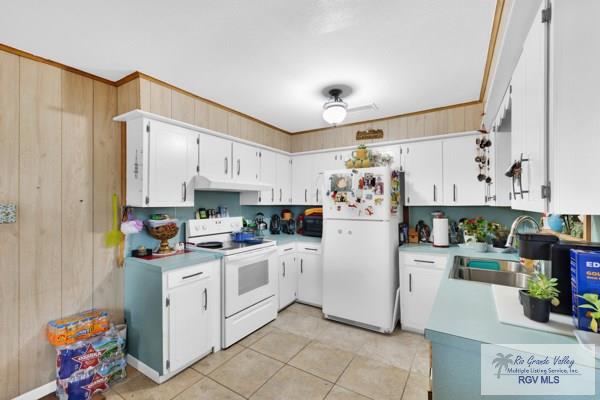 kitchen featuring white appliances, light countertops, and white cabinets