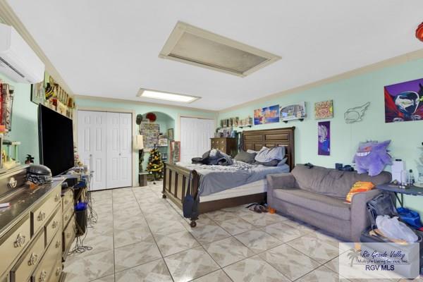 bedroom with attic access, multiple closets, and a wall mounted AC