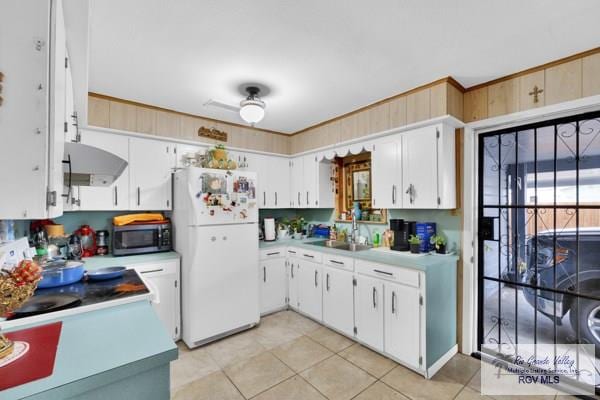 kitchen featuring light countertops, stainless steel microwave, freestanding refrigerator, white cabinets, and a sink