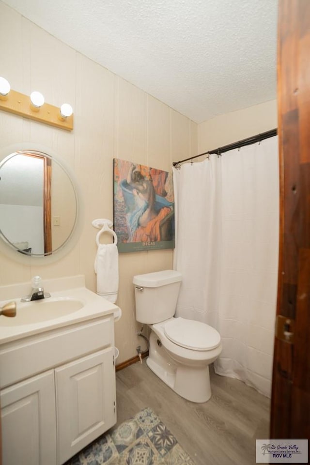 bathroom with a shower with shower curtain, toilet, wood finished floors, a textured ceiling, and vanity