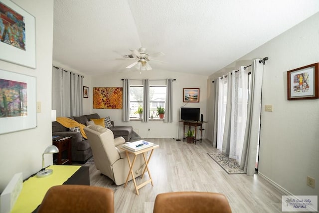 living room featuring vaulted ceiling, a textured ceiling, light wood finished floors, and ceiling fan