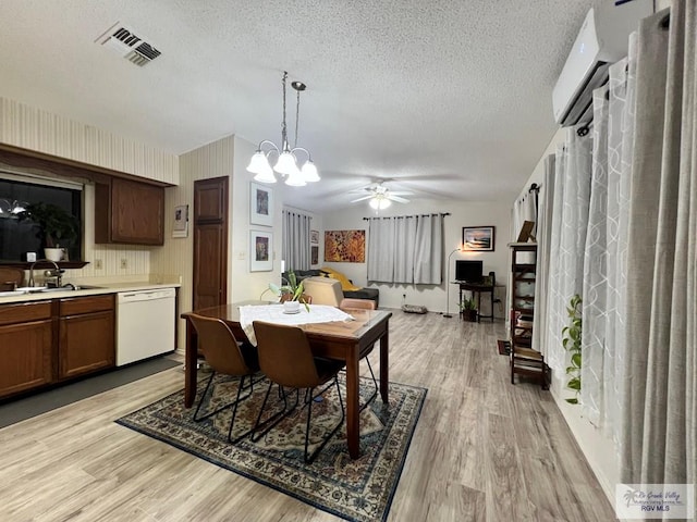 dining space featuring light wood-type flooring, visible vents, a textured ceiling, and ceiling fan with notable chandelier