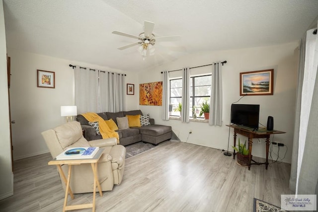 living room featuring light wood-style floors, lofted ceiling, ceiling fan, and a textured ceiling