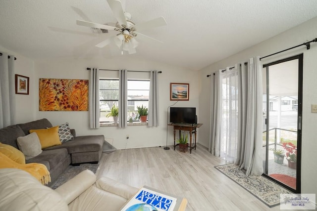 living area with plenty of natural light, a textured ceiling, vaulted ceiling, and wood finished floors