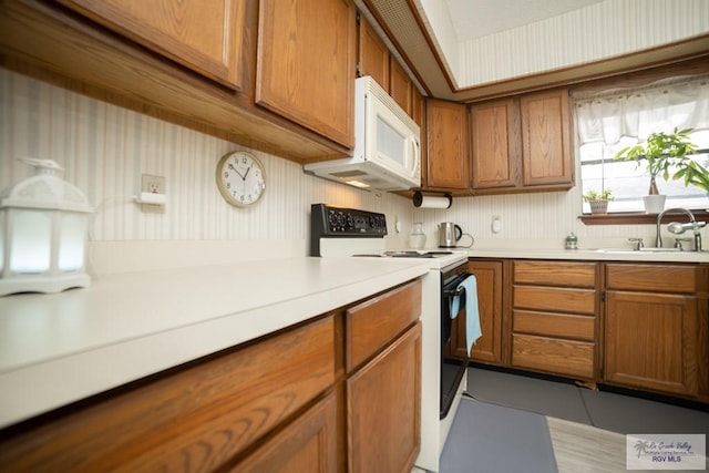 kitchen with light countertops, white appliances, brown cabinets, and a sink