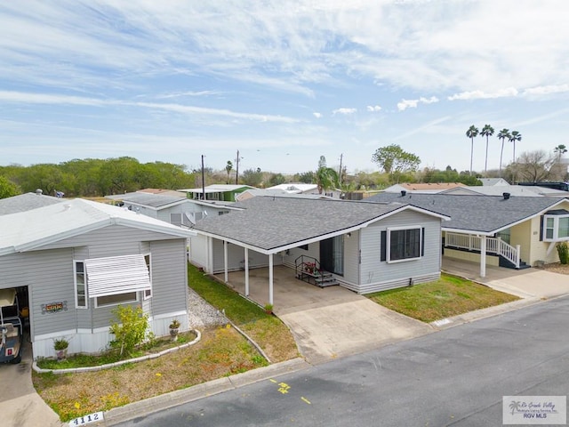 view of front of home with a shingled roof, a residential view, an attached carport, and concrete driveway