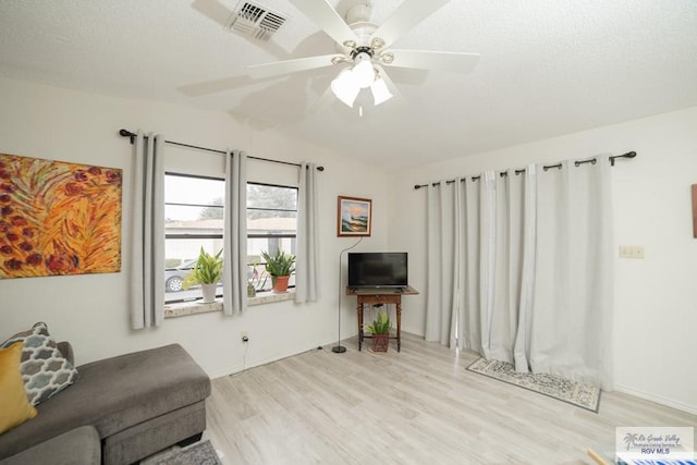 living room featuring a textured ceiling, wood finished floors, visible vents, a ceiling fan, and vaulted ceiling