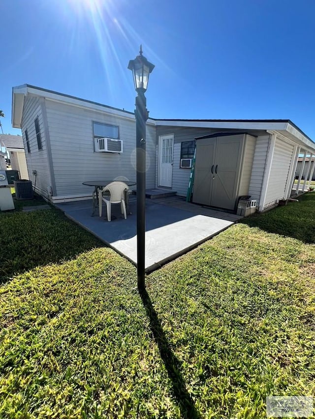 back of house with an outbuilding, a yard, a patio area, a shed, and cooling unit