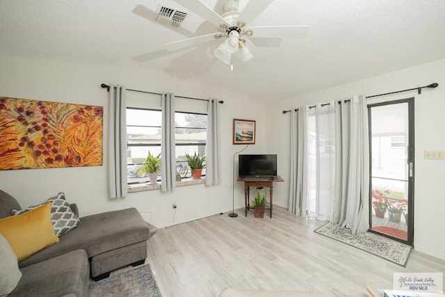 sitting room with a healthy amount of sunlight, visible vents, vaulted ceiling, and wood finished floors