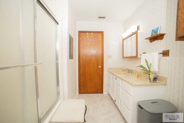 bathroom featuring a shower stall, vanity, and wallpapered walls