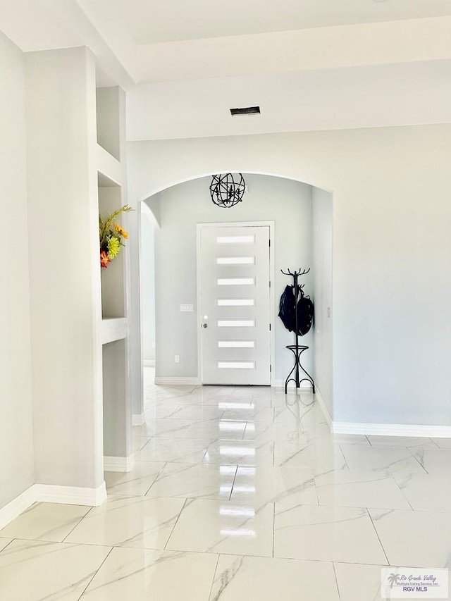 entrance foyer with marble finish floor, baseboards, and arched walkways