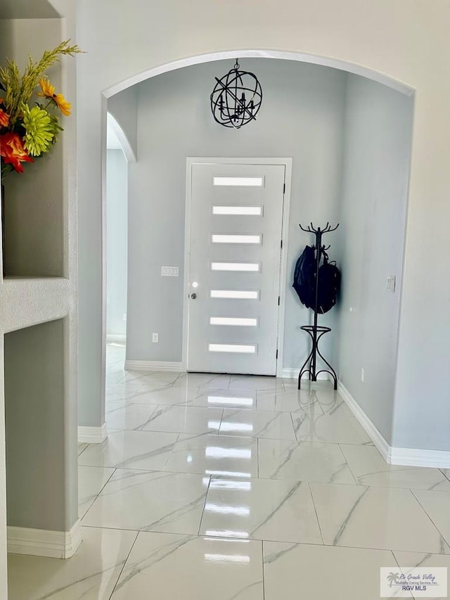 entryway with arched walkways, marble finish floor, and baseboards