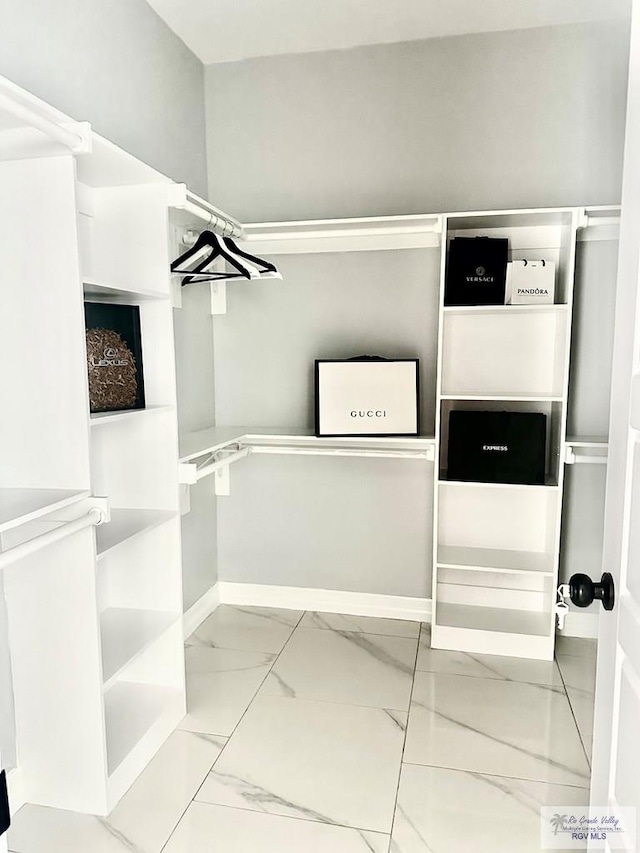 walk in closet featuring marble finish floor