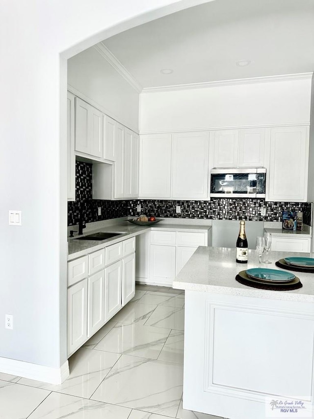 kitchen featuring stainless steel microwave, white cabinets, and light countertops