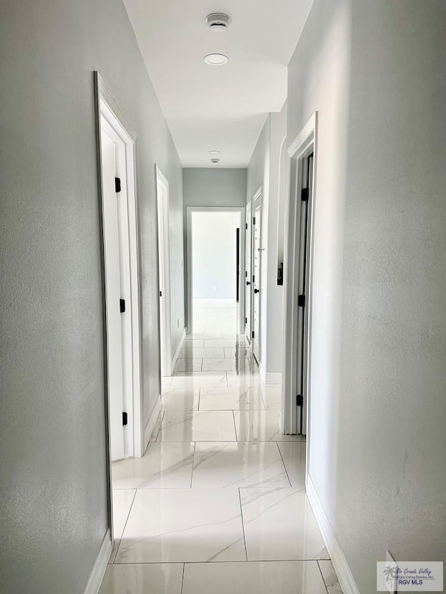 hall with marble finish floor and baseboards