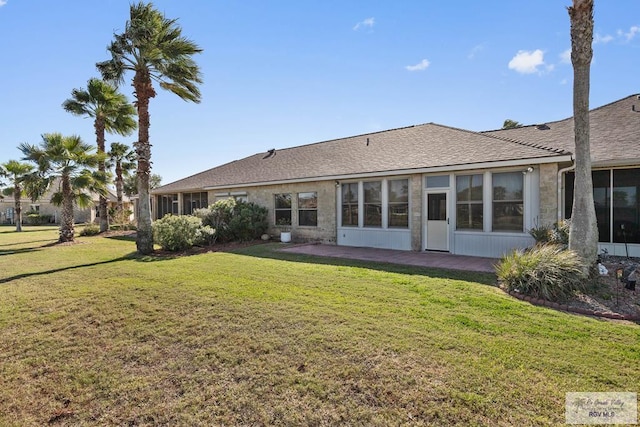 rear view of property with a yard, roof with shingles, and a patio