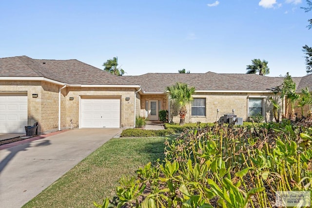 ranch-style home with a shingled roof, an attached garage, cooling unit, driveway, and a front lawn