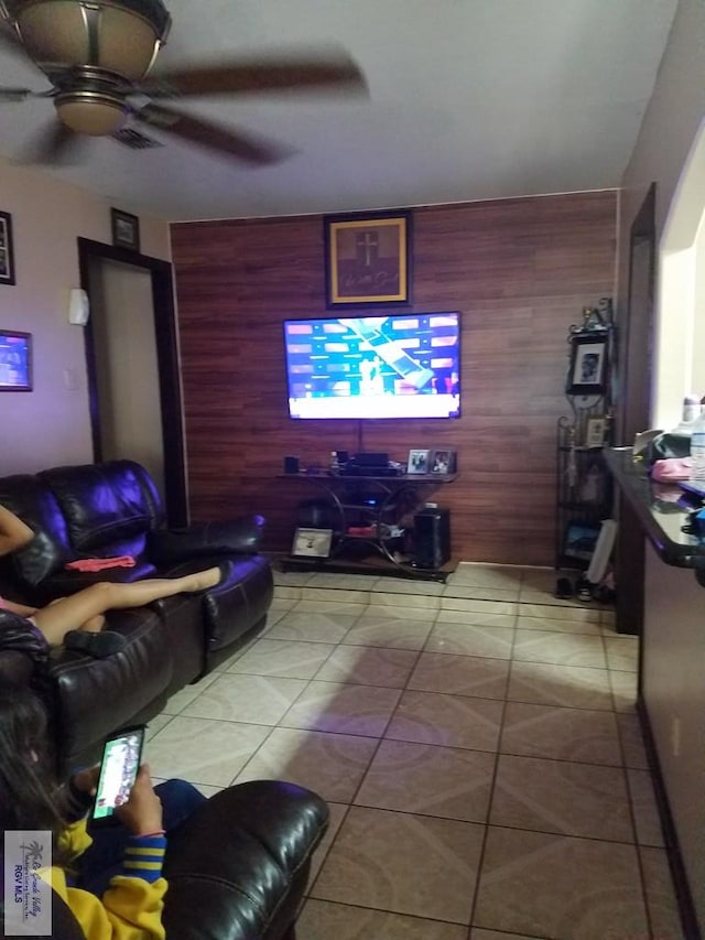 tiled living area featuring wood walls and ceiling fan