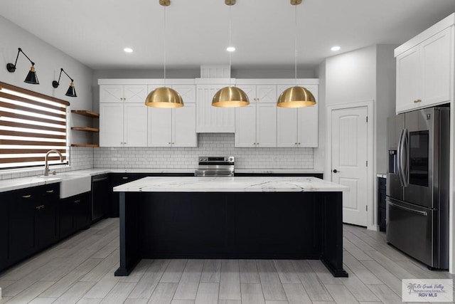 kitchen with pendant lighting, a kitchen island, sink, and stainless steel appliances