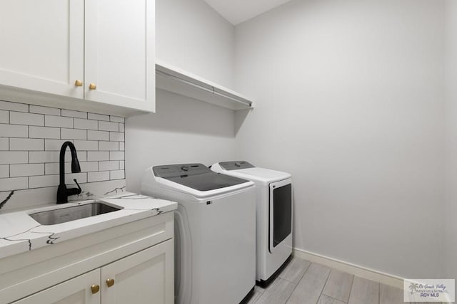 clothes washing area with sink, light hardwood / wood-style flooring, cabinets, and independent washer and dryer