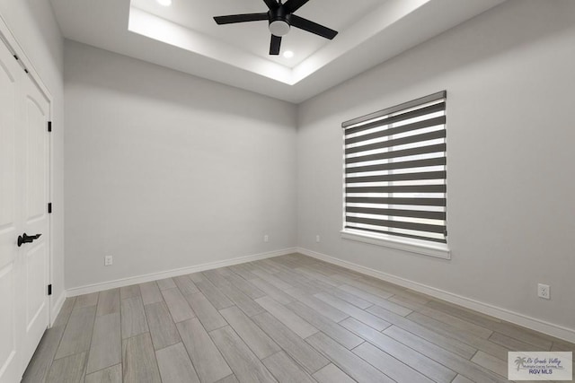 spare room featuring light hardwood / wood-style floors, a raised ceiling, and ceiling fan