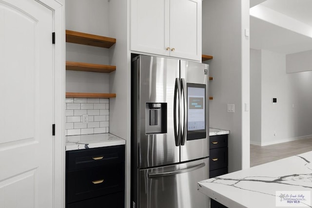 kitchen featuring stainless steel refrigerator with ice dispenser, tasteful backsplash, light stone counters, wood-type flooring, and white cabinets