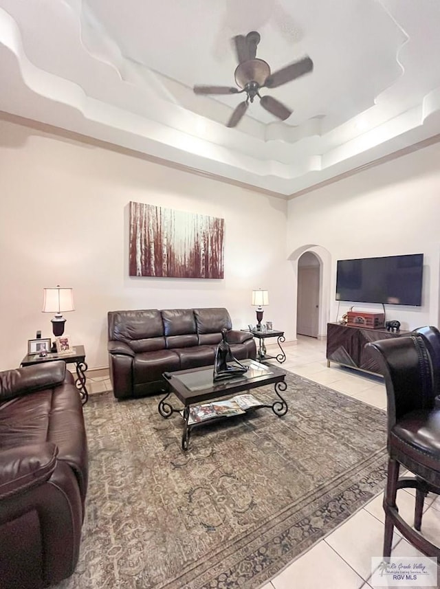 tiled living room featuring ceiling fan and a tray ceiling