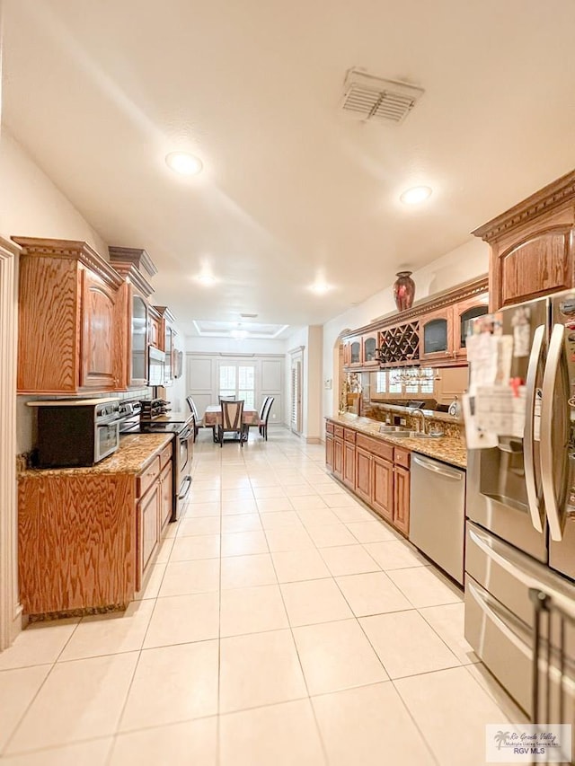 kitchen with light stone countertops, appliances with stainless steel finishes, and light tile patterned floors